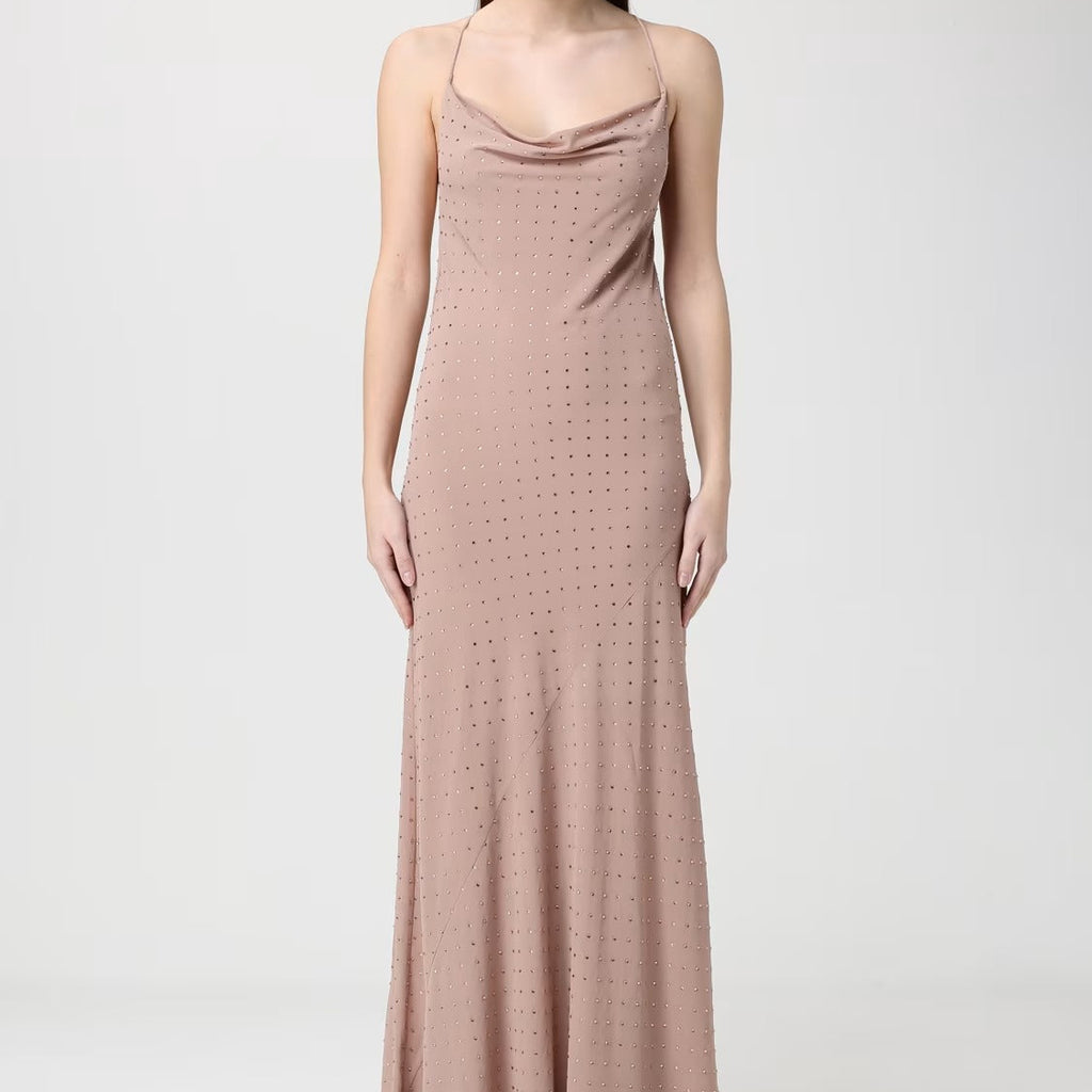 A woman modeling a floor-length, sleeveless cowl-neck dress in a dusty rose pink color with a subtle dotted texture, set against a plain light gray studio background.