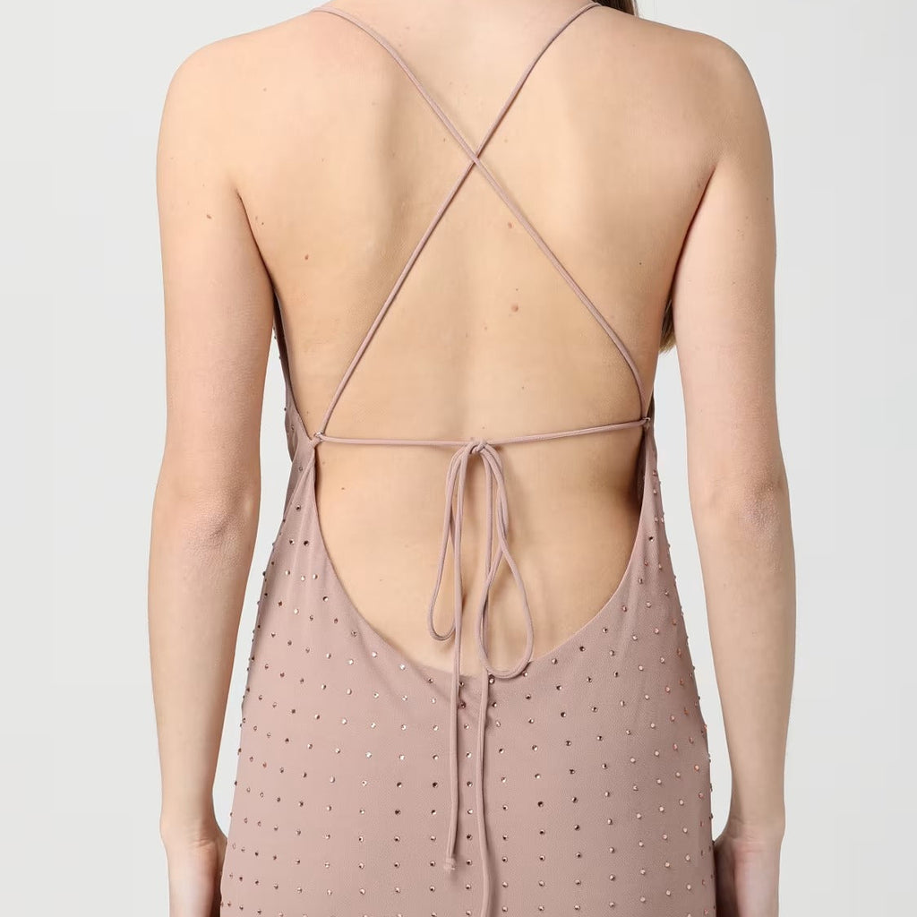 Rear view of a woman wearing a dusty rose slip dress with a dotted texture and crisscross back straps.